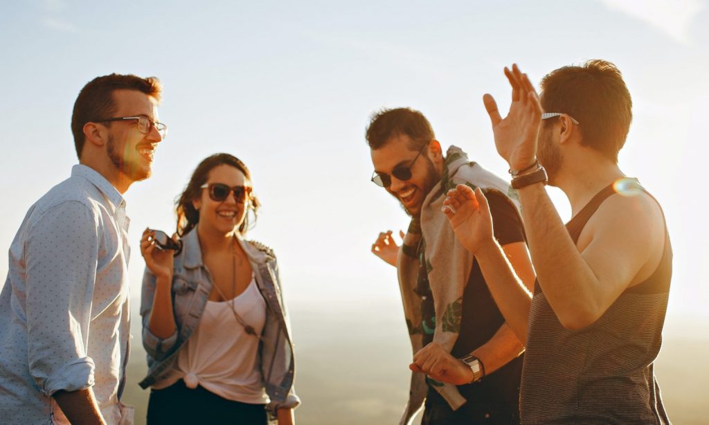 three men and one woman laughing during daytime