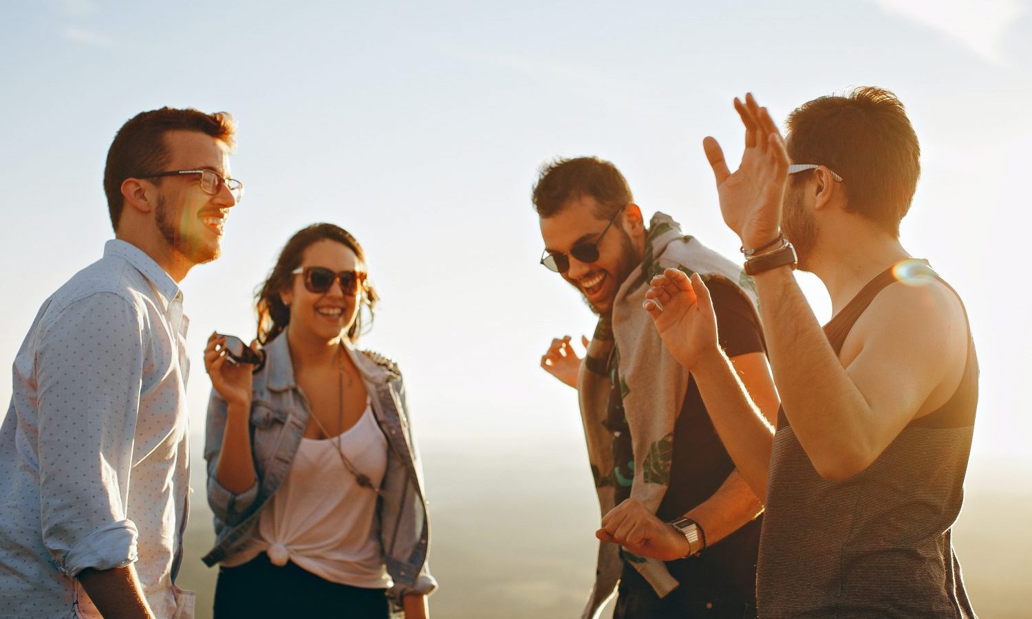 three men and one woman laughing during daytime